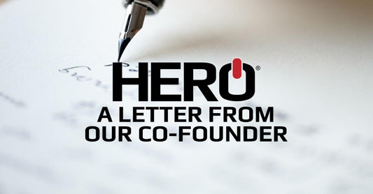 A pen tip writing on a piece of paper in the background. The HERO logo is shown followed by the text that reads: A letter from our co-founder