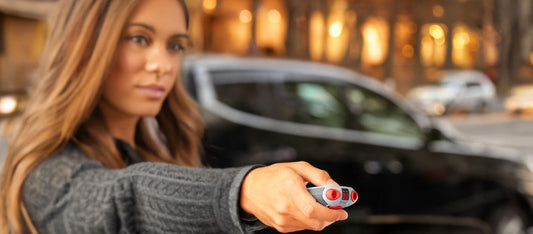 A woman standing near a street aims her AIIRO® non-lethal defense tool.