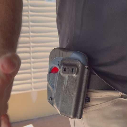 A close up of the HERO 2020 device being drawn from a holster on someone's hip